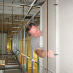 Installing hold down clips on the back of vertical ceiling tiles in a suspended ceiling drop